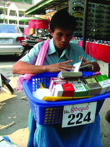 หนุ่มชาวพม่าหาเวลาว่างจากการขายสินค้ามานั่งอ่านหนังสือ
